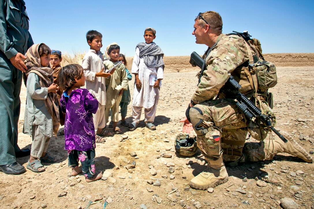 U.S. Army Staff Sgt. Matthew Parsons interacts with Afghan children during a partnered operation with Afghan civil police officers in Delaram, Helmand province, Afghanistan, May 26, 2013. Parson is assigned to the Police Advisor Team Deleram.  
