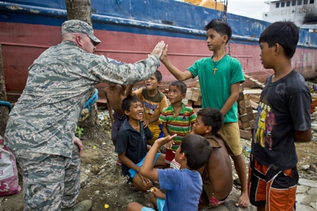 U.S. Air Force Master Sgt. Aaron Walters high fives a Philippine child during Balikatan 2014 while surveying the area of Tacloban, Philippines, May 10, 2014. The exercise, in its 30th year, is a U.S.- Philippines military training exercise. Waiters is the superintendent of chapel operations assigned to the 35th Fighter Wing, based on Misawa Air Base, Japan. 