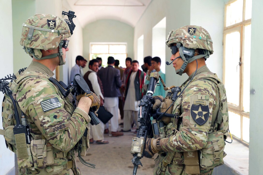 U.S. Army 1st Lt. Robert Wolfe, right, and U.S. Army Spc. Michael Jones, left, provide security during a key leader engagement with Farah's provincial education director at Aboonaser Farahi high school in Farah City, Afghanistan, May 13, 2013. Wolfe, a platoon leader, and Jones are assigned to Provincial Reconstruction Team Farah.  
