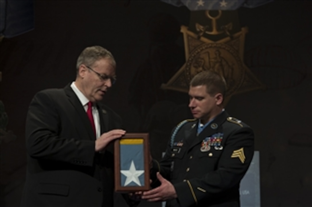 Deputy Defense Secretary Bob Work presents the Medal of Honor flag to former Army Sgt. Kyle J. White, the most recent Medal of Honor recipient, during a ceremony to induct White into the Hall of Heroes at the Pentagon, May 14, 2014. President Barack Obama awarded White the medal for courageous actions while serving as a platoon radio telephone operator during combat operations against an armed enemy in Afghanistan's Nuristan province, Nov. 9, 2007.