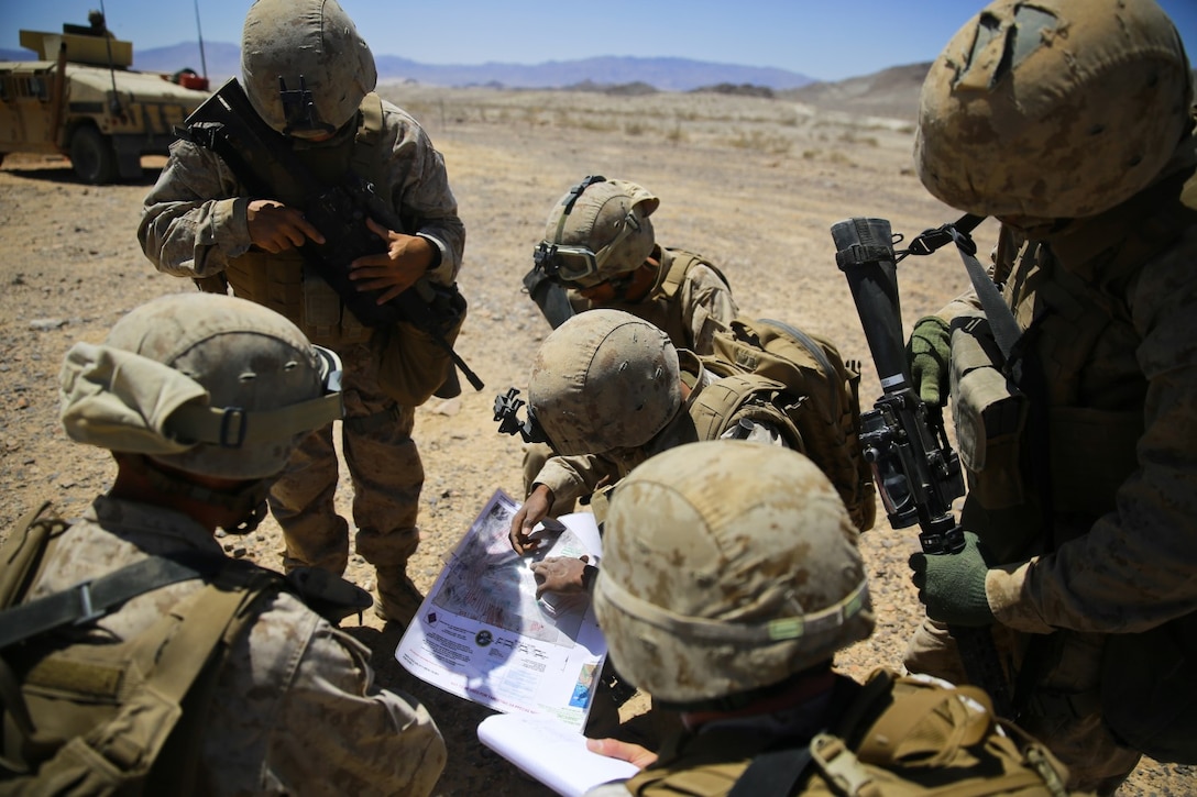 Marines with Headquarters Battalion, 1st Marine Division, review a route before conducting a security patrol during Exercise Desert Scimitar at Marine Corps Air Ground Combat Center Twentynine Palms, Calif., May 12, 2014. The security platoon is comprised of Marines of varying jobs including band members, motor transport operators and data wire technicians. They come together to provide security for 1st Marine Division during the exercise, maintaining an entry control point and conducting patrols around the camp. (U.S. Marine Corps photograph by Sgt. Timothy Lenzo/RELEASED)