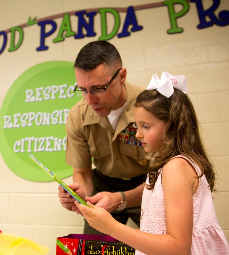 Brig. Gen. Robert Castellvi, the commanding general of Marine Corps Installations East – Marine Corps Base Camp Lejeune gives Evoli, a military child, a book after meeting her for lunch at Parkwood Elementary School in Jacksonville, N.C, May 7. Evoli won the lunch with Castellvi at a raffle held during the All-American Family Night, an event hosted by the Camp Lejeune School Liaison in April.