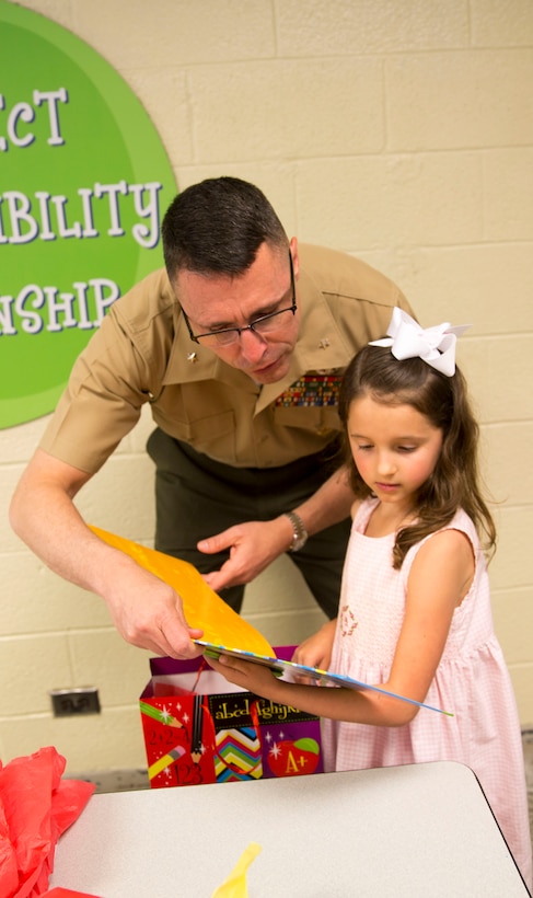 Brig. Gen. Robert Castellvi, the commanding general of Marine Corps Installations East – Marine Corps Base Camp Lejeune gives Evoli, a military child, a book after meeting her for lunch at Parkwood Elementary School in Jacksonville, N.C, May 7. Evoli won the lunch with Castellvi at a raffle held during the All-American Family Night, an event hosted by the Camp Lejeune School Liaison in April.