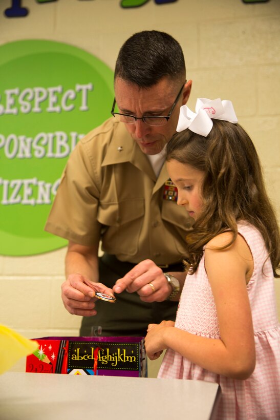 Brig. Gen. Robert Castellvi, the commanding general of Marine Corps Installations East – Marine Corps Base Camp Lejeune gives  Evoli, a military child, a challenge coin after meeting her for lunch at Parkwood Elementary School in Jacksonville, N.C, May 7. Evoli won the lunch with Castellvi at a raffle held during the All-American Family Night, an event hosted by the Camp Lejeune School Liaison in April.