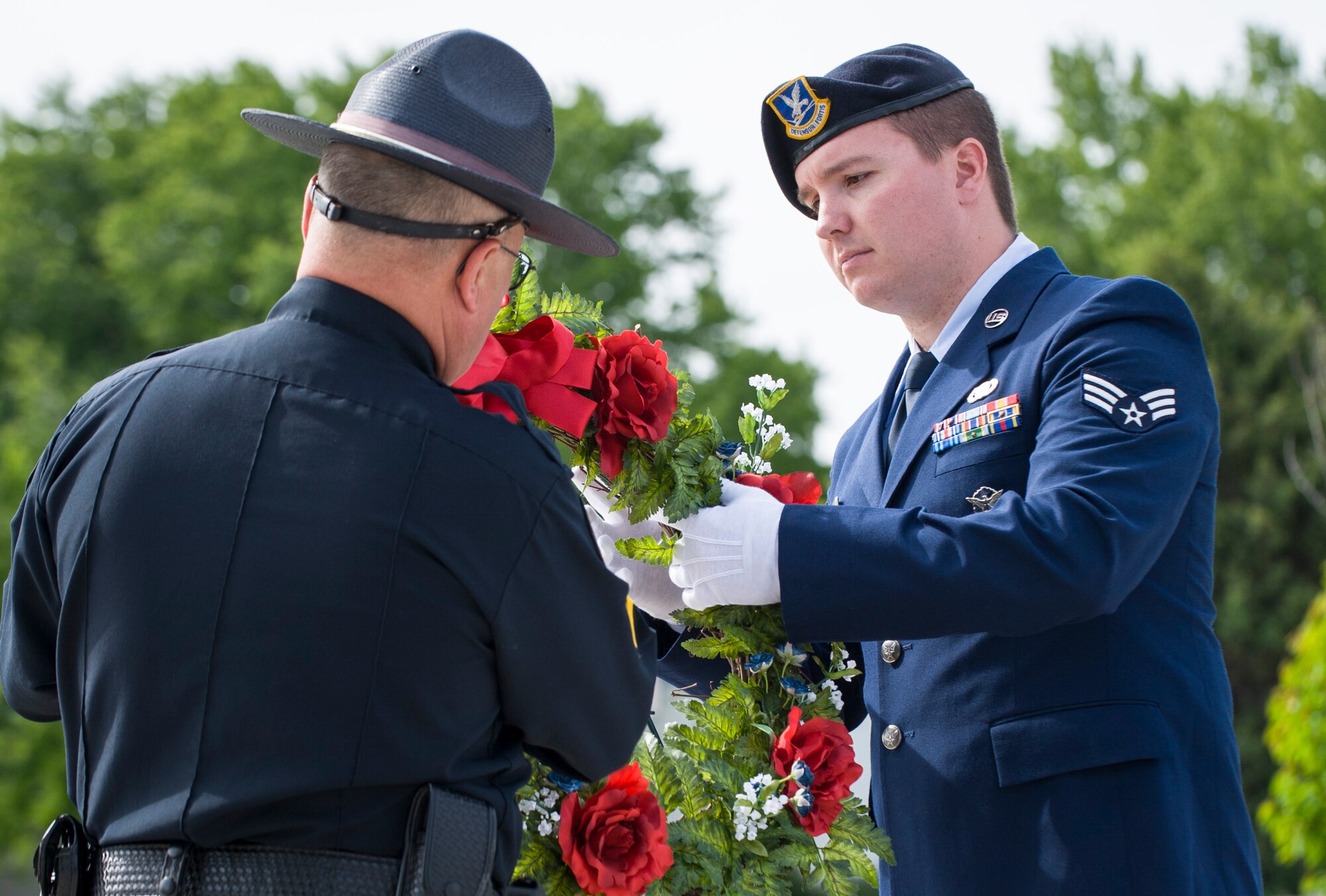 Corporal Stan Winings, Mountain Home Police Department community affairs, and Senior Airman Christopher Hotine, 366th Security Forces Squadron defender, displays a wreath during Peace Officers Memorial Day retreat ceremony at Mountain Home Air Force Base, Idaho, May 15, 2014. Peace Officers Memorial Day was designated by President John F. Kennedy to fall on May 15th to honor all law enforcement officers who lost their lives in the line of duty. (U.S. Air Force photo by Staff Sgt. Roy Lynch III/RELEASED)