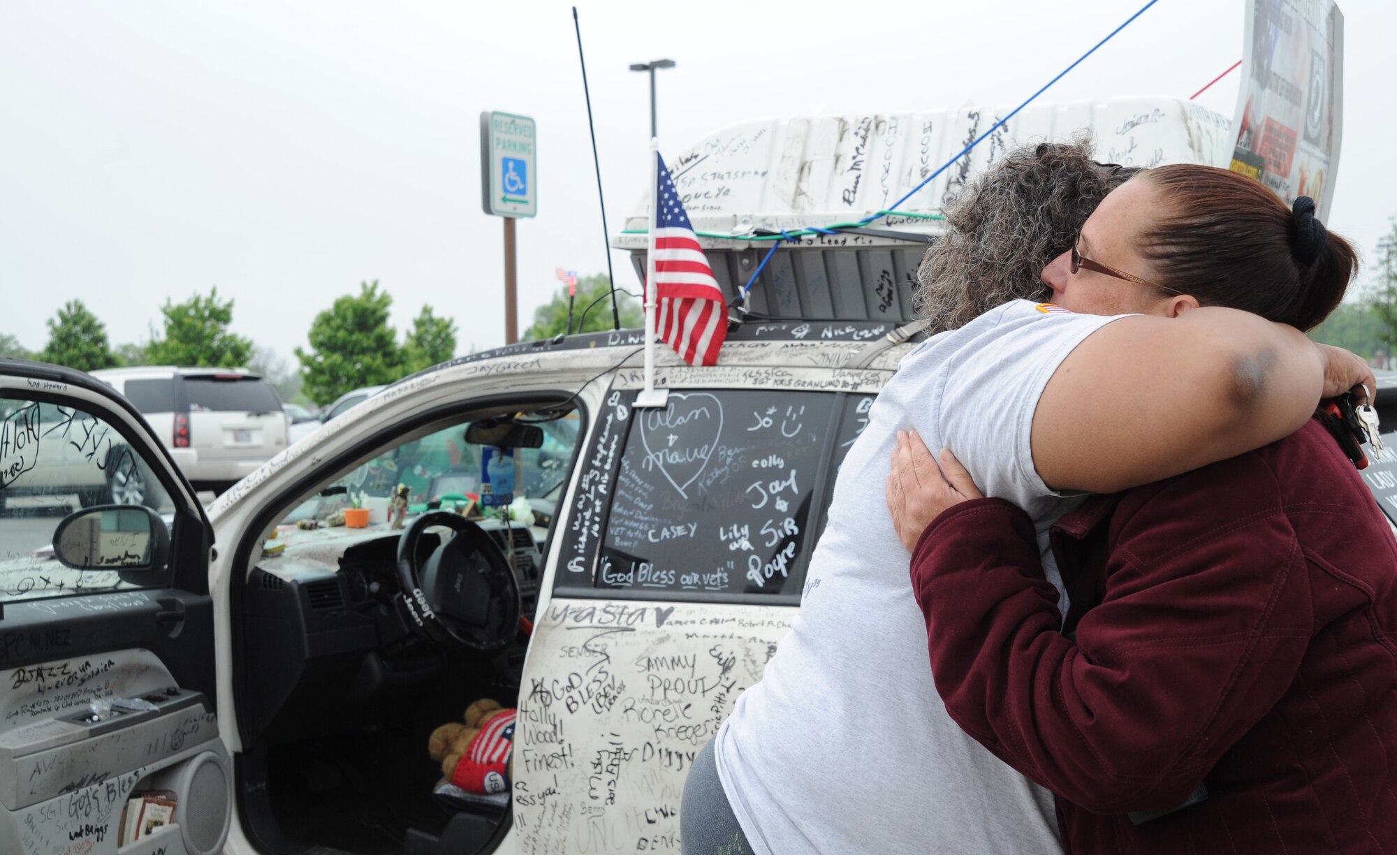 Lisa Groves and Shannonlee Stout share a hug in front of a car covered in signatures of American, Canadian and Mexican military veterans along with civilian messages of support at Joint Base Andrews, Md., May 14, 2014. The car belongs to Groves, who served in the U.S. Army, a veteran advocate. She is on her second nationwide journey promoting awareness of veterans’ struggles which began June 2, 2013. The car is full of clothes, hygiene items, towels, shoes, bottled water and canned food for veterans in need. Stout is an Air Force District of Washington budget analyst. (U.S. Air Force photo/Master Sgt. Tammie Moore)