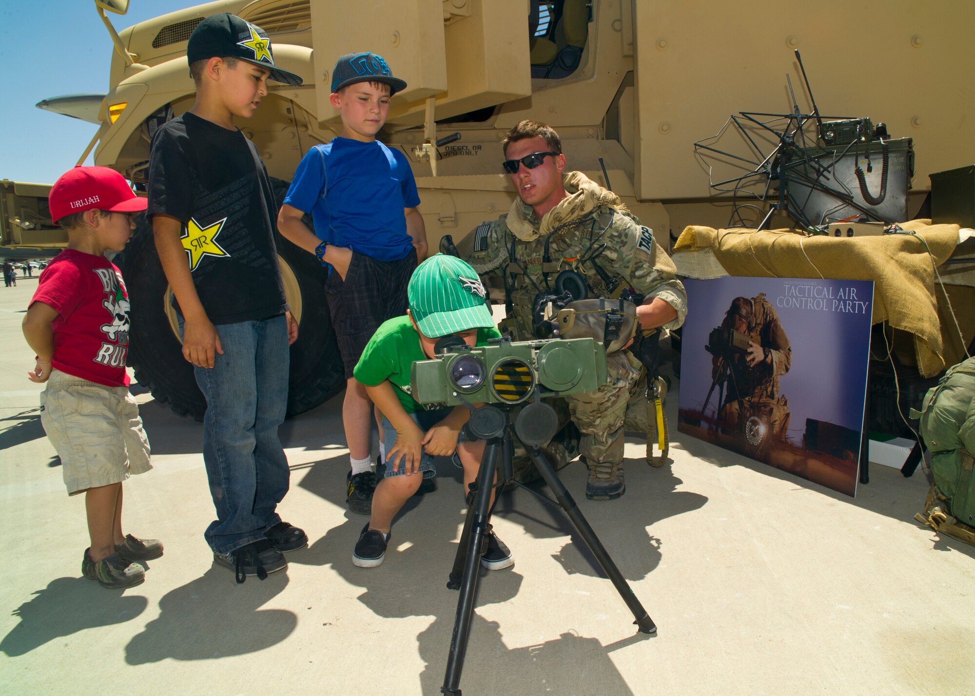 Airman 1st Class Eric Sanders, Tactical Air Control Party with the 7th Air Support Operations Squadron at Ft. Bliss, Texas, shows children equipment TACP uses during operations at the Open House at Holloman Air Force Base, N.M., May 10. Team Holloman hosted an Open House showcasing over 50 aircraft and the day-to-day duties of Holloman Airmen. With live flying demonstrations and static displays, thousands of guests attended the event to get a close-up look at the base’s assets and capabilities. Guests were able to view various aircraft, visit numerous vendors, and witness ground demonstrations from squadrons around the base. (U.S. Air Force photo by Airman 1st Class Leah Ferrante/Released) 