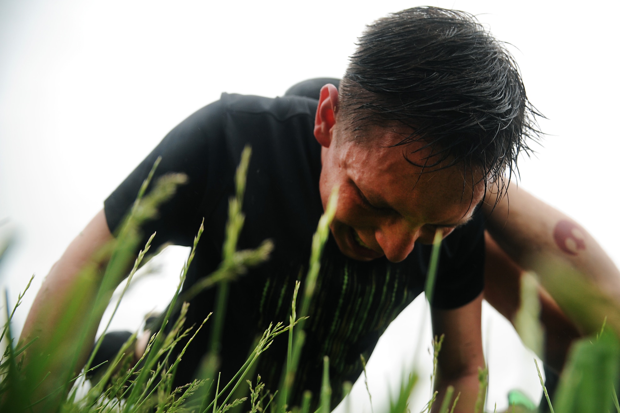 Airman 1st Class Dennis Martin helps team members perform fire-team push-ups during the last obstacle during an obstacle for Police Week May 13, 2014, Scott Air Force Base, Ill. Throughout the obstacle course teams were competing in a race, performing ruck relays, weapons disassembly/ re-assembly while blindfolded and a low crawl course. (U.S. Air Force photo/Senior Airman Tristin English)