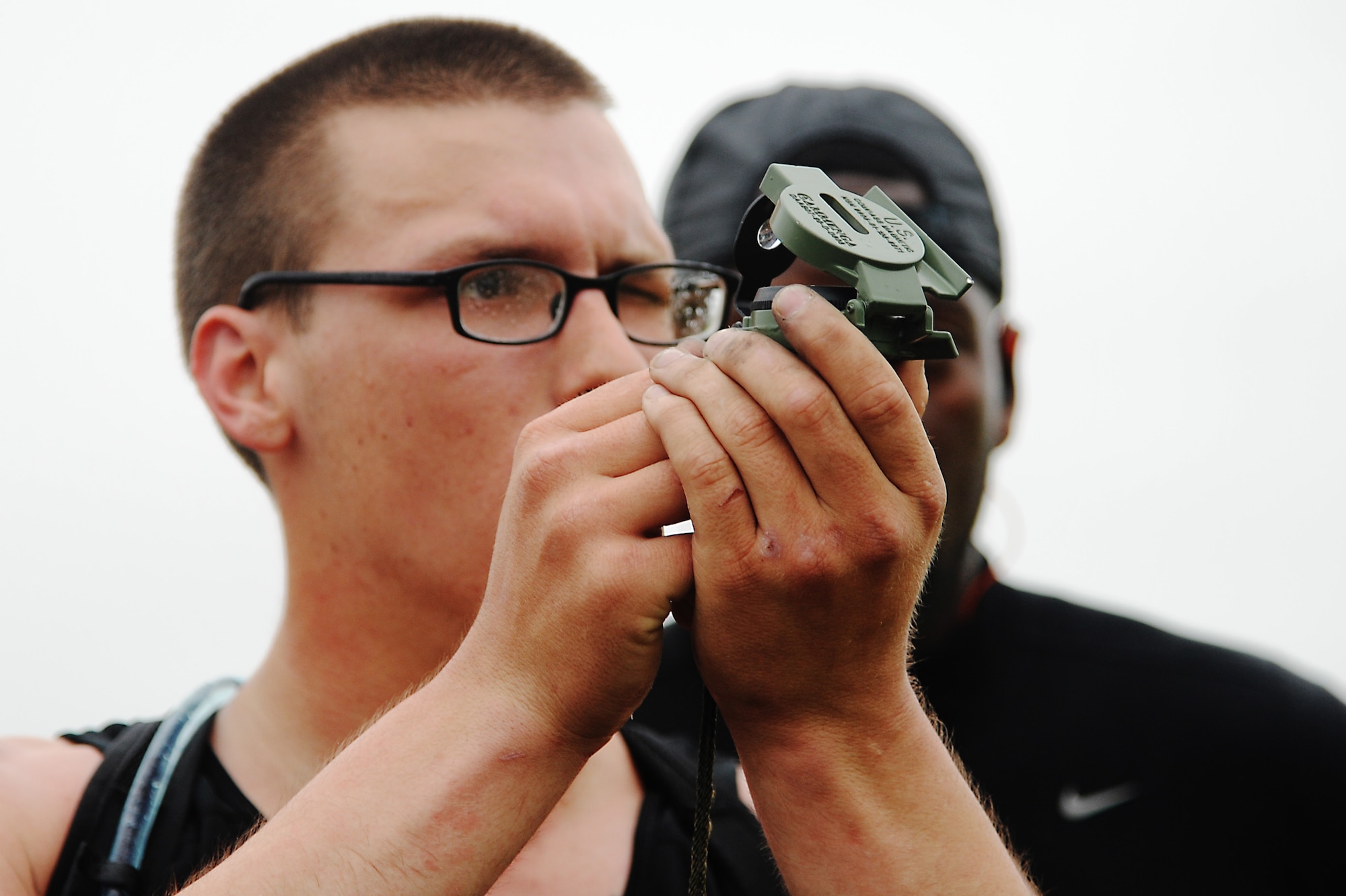 Airman 1st Class Aaron Lauriton looks through a military compass for the range of five different places during an obstacle for Police Week May 13, 2014, Scott Air Force Base, Ill. The obstacle had five fixed objects at a predetermined distances. For every meter over the team did that amount of push-ups divided between themselves. (U.S. Air Force photo/Senior Airman Tristin English)