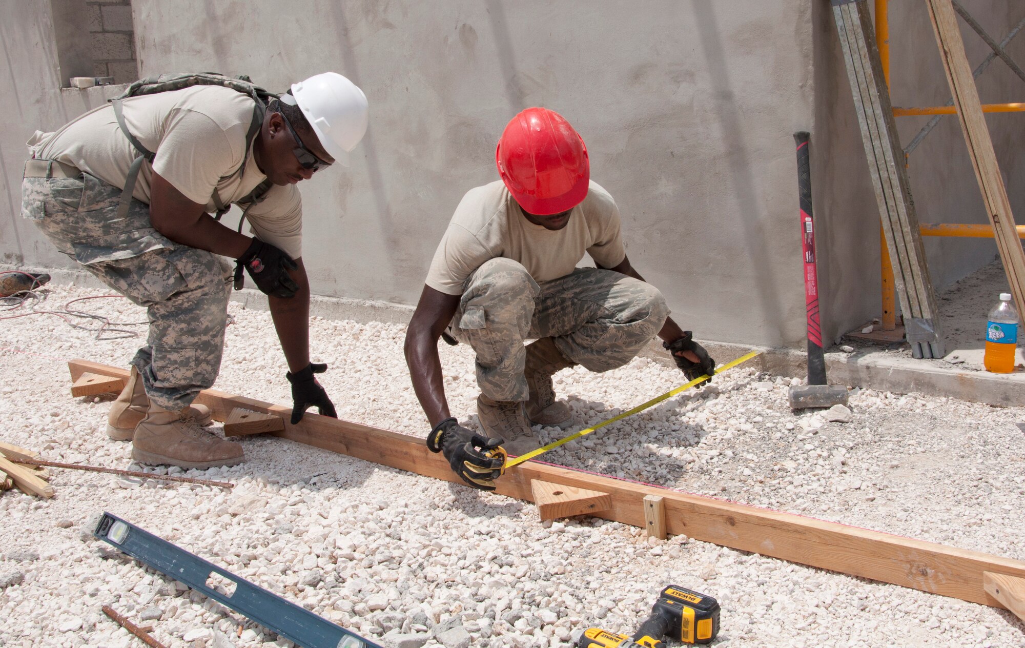 U.S. Army Sgt. Timothy Puckett, a carpentry and masonry specialist deployed from the Louisiana National Guard's 1023rd Vertical Engineer Company, assists a U.S. Air Force engineer with laying frames to pour a concrete sidewalk May 13, 2014, at the Hattieville Government School in Hattieville, Belize. BDF and U.S. service members are working together to build five school buildings and one medical facility in Belize during New Horizons Belize 2014. New Horizons is an annual event coordinated between the U.S. and the host nation to provide mutual training opportunities in the fields of health care and civil engineering. (U.S. Air Force photo by Tech. Sgt. Kali L. Gradishar/Released)