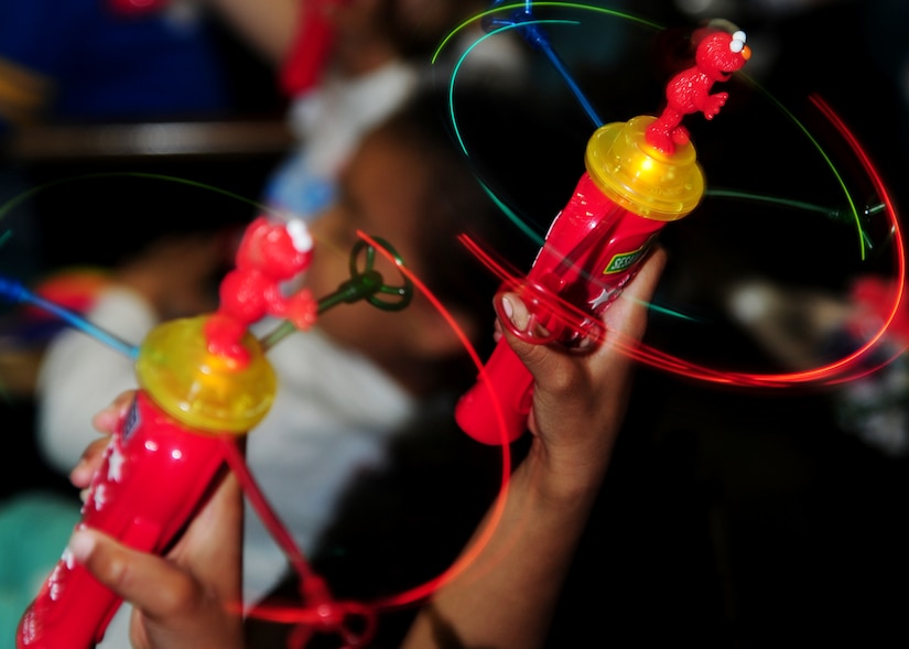 Children raise toys in the air during the Sesame Street/USO Experience for Military Families at the base theater on Joint Base Andrews, Md., May 14, 2014. The performances, brought to them by the USO, told the story of Katie, a military child who just found out she will be relocating to a new place with her family. (U.S. Air Force photo/ Senior Airman Aaron Stout/released)