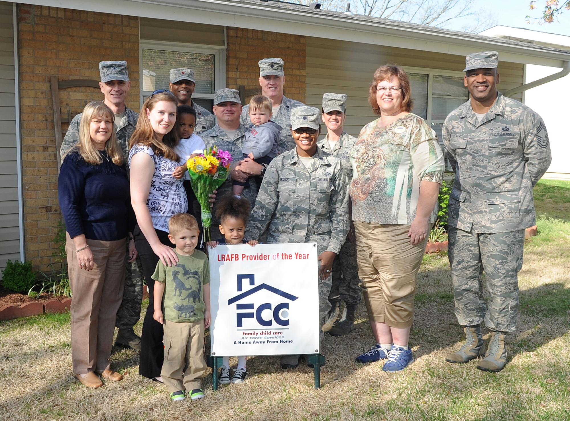 Malissa Kaye along with the Family Child Care supervisors and base leadership, pose for a photo behind the Little Rock Air Force Base Provider of the Year sign April 17, 2014, at Little Rock Air Force Base, Ark. Kaye provided day and night care for military service members, earning her the recognition. (U.S. Air Force photo by Staff Sgt. Caleb Pierce)