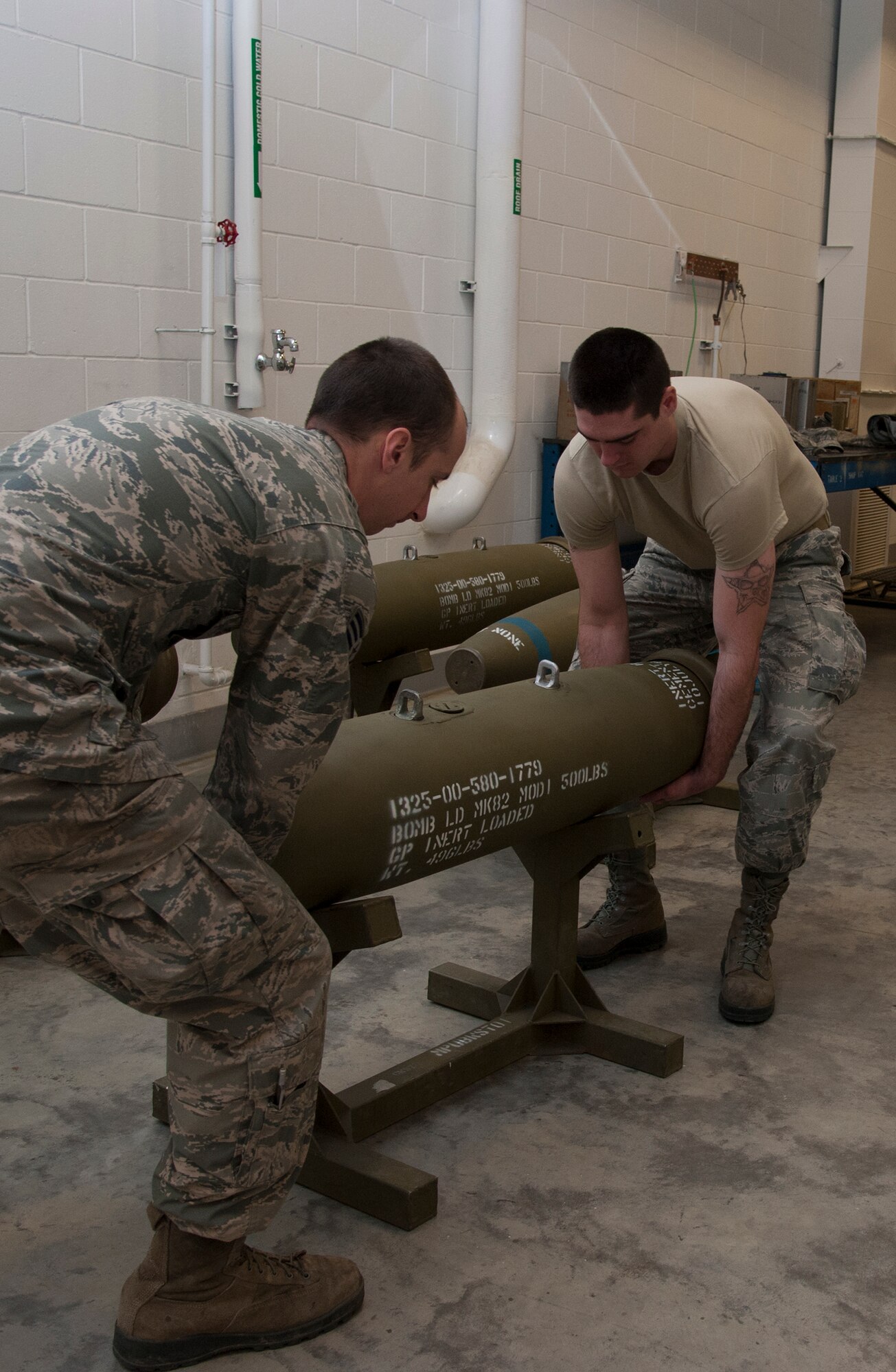Airmen from the 5th Munitions Squadron, move a training bomb to the middle of the floor during a training session at Minot Air Force Base, N.D., May 7, 2014. The Airmen worked to build dummy bombs to prepare for an upcoming exercise. (U.S. Air Force photo/Senior Airman Andrew Crawford)