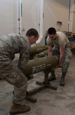 Airmen from the 5th Munitions Squadron, move a training bomb to the middle of the floor during a training session at Minot Air Force Base, N.D., May 7, 2014. The Airmen worked to build dummy bombs to prepare for an upcoming exercise. (U.S. Air Force photo/Senior Airman Andrew Crawford)