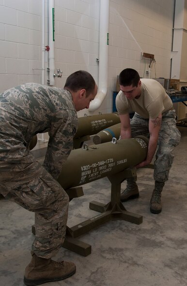 Airmen from the 5th Munitions Squadron, move a training bomb to the middle of the floor during a training session at Minot Air Force Base, N.D., May 7, 2014. The Airmen worked to build dummy bombs to prepare for an upcoming exercise. (U.S. Air Force photo/Senior Airman Andrew Crawford)