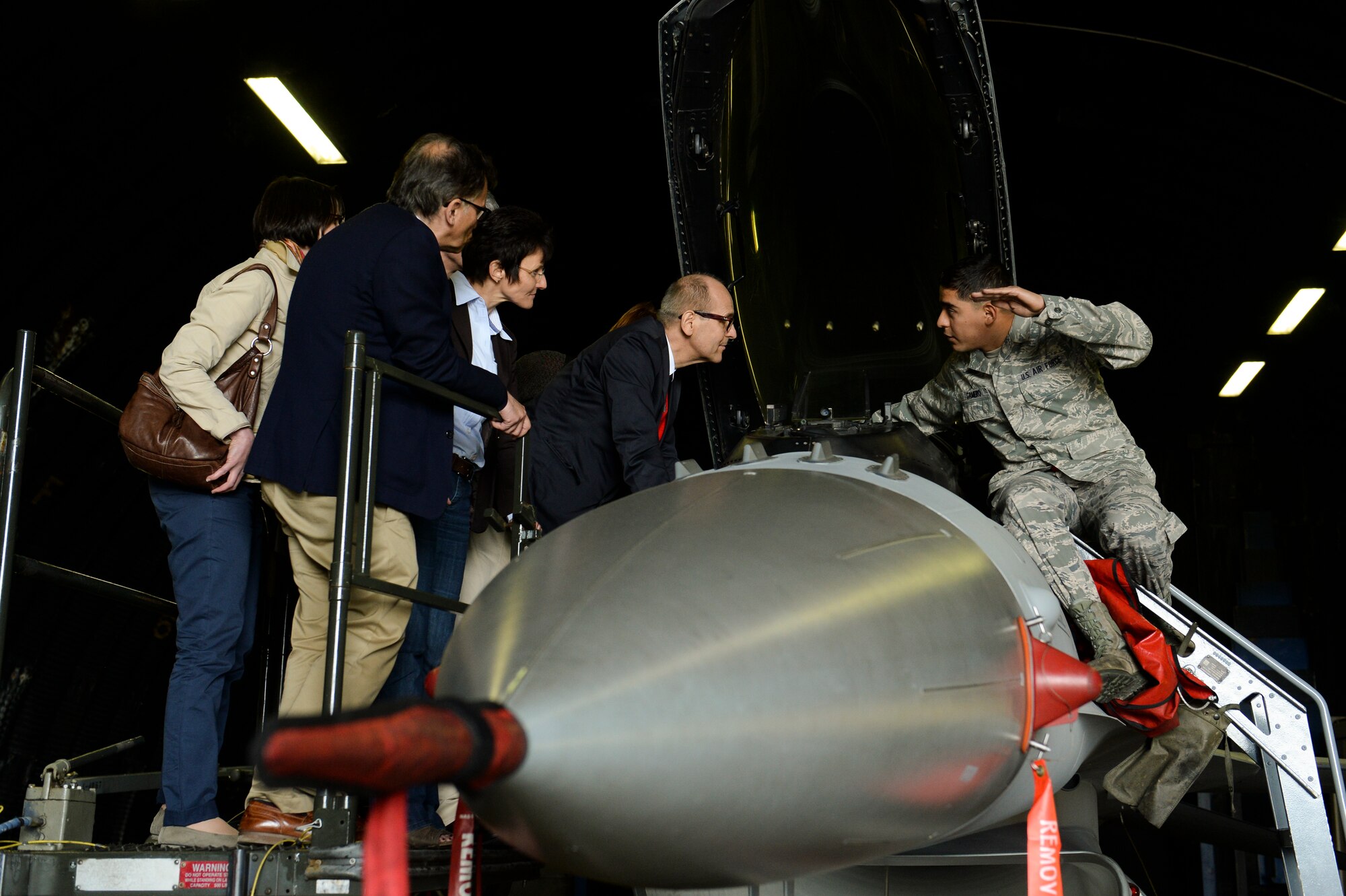 U.S. Air Force Senior Airman Ramiro Gamero, a 52nd Aircraft Maintenance Squadron crewchief from Riverside, Calif., talks to German medical providers about the operations of an F-16 Fighting Falcon fighter aircraft during a Host Nation Hospital Leader Tour May 14, 2014, at Spangdahlem Air Base, Germany. Local medical providers toured based facilities and talked to Airmen. (U.S. Air Force photo by Senior Airman Rusty Frank/Released)