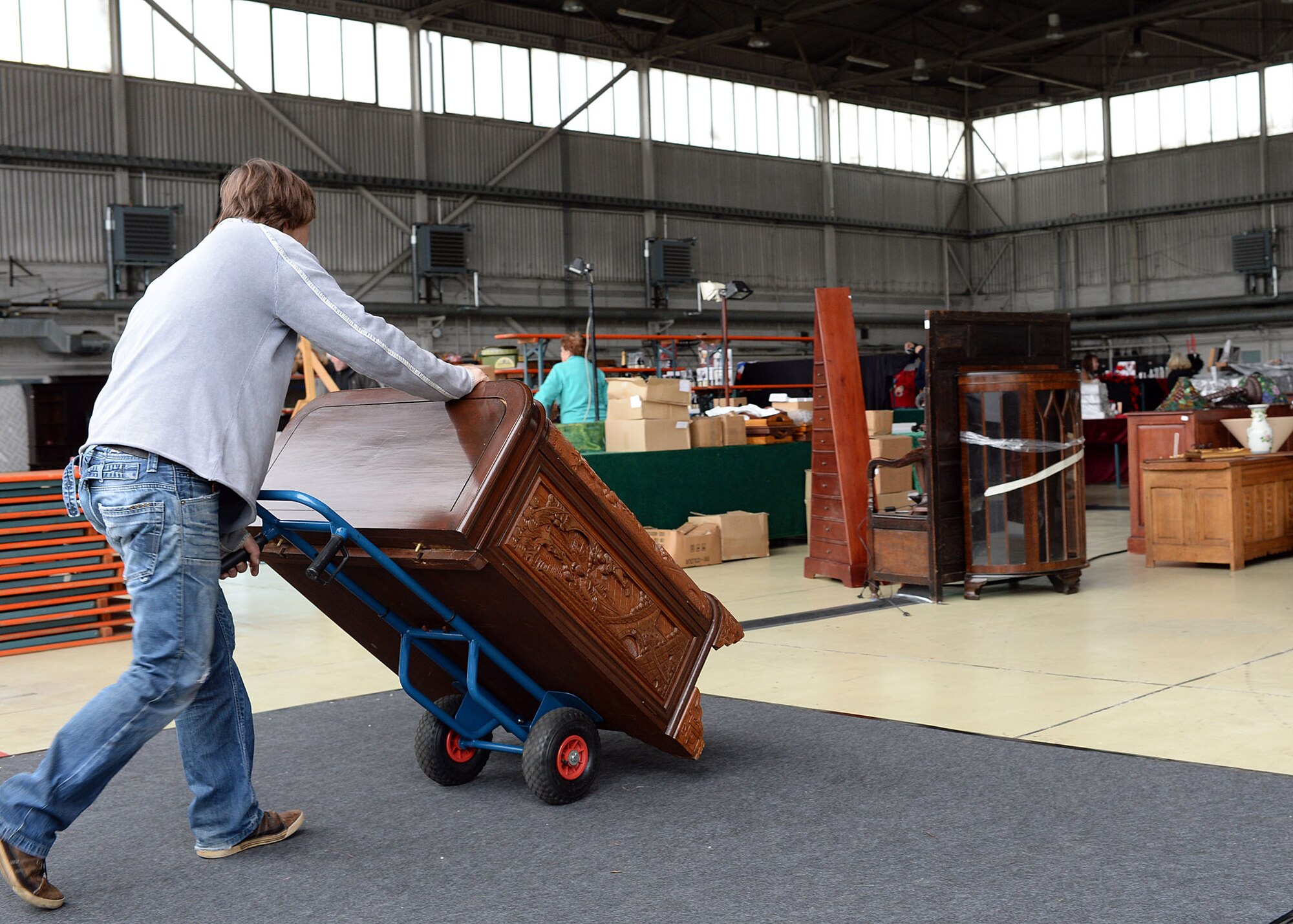 A vendor wheels a piece of furniture to his booth in Hangar 2 May 15, 2014, for the upcoming Spring Bazaar at Spangdahlem Air Base, Germany. Nearly a dozen countries are participating at the Bazaar and will sell wares that include food, furniture, artwork and home décor. (U.S. Air Force photo by Staff Sgt. Daryl Knee/Released)