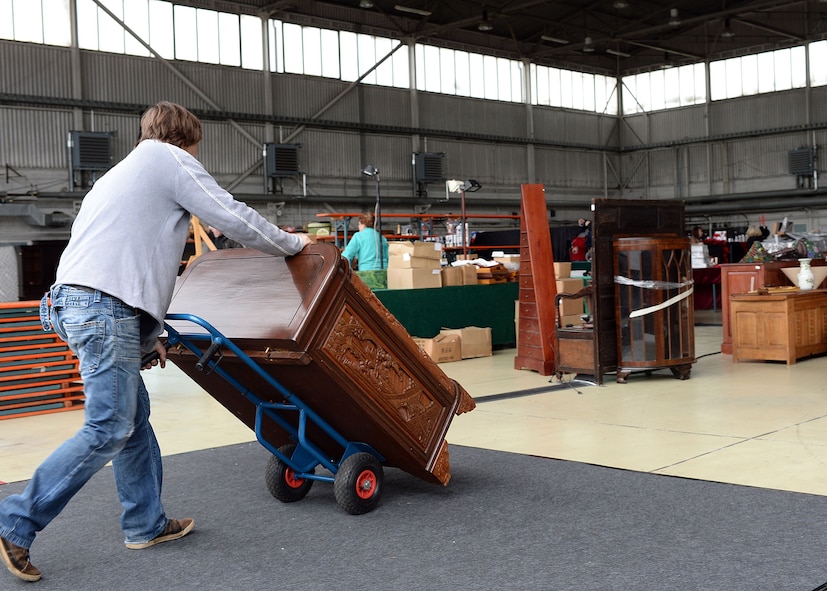 A vendor wheels a piece of furniture to his booth in Hangar 2 May 15, 2014, for the upcoming Spring Bazaar at Spangdahlem Air Base, Germany. Nearly a dozen countries are participating at the Bazaar and will sell wares that include food, furniture, artwork and home décor. (U.S. Air Force photo by Staff Sgt. Daryl Knee/Released)