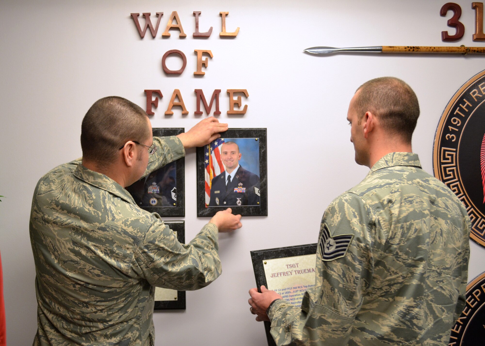 HANSCOM AIR FORCE BASE, Mass. – Tech. Sgt. Jeffrey Trueman (right) looks on as Capt. Carlos N. Barrios, 319th Recruiting Squadron Support Flight commander, hangs a portrait of Trueman on the 319 RCS “Wall of Fame” here, May 1. Trueman, who just transferred to Goodfellow Air Force Base, Texas to return to his career field as a fire protection instructor, was recently named as one of Air Education and Training Command’s Outstanding Airmen of the Year and was a finalist for the Air Force 12 Outstanding Airmen of the Year. He also was named the AETC’s Outstanding Recruiter of the Year and was promoted to technical sergeant under the Stripes for Exceptional Performer’s Program. (Courtesy photo)