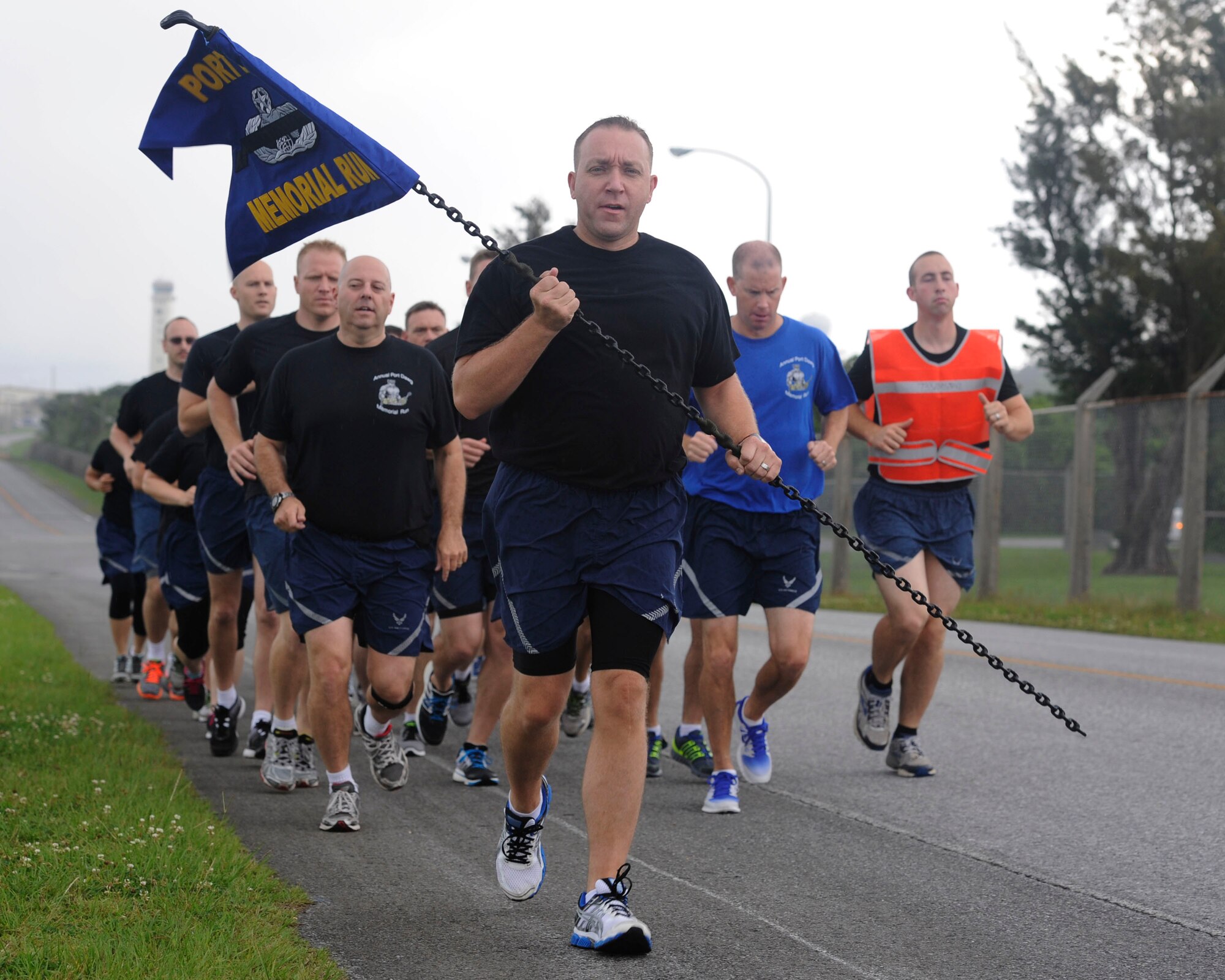 Lt. Col. Derek Stuart, 733rd Air Mobility Squadron commander, leads a memorial run on Kadena Air Base, Japan, May 15, 2014, honoring the 14 aerial transporters, also known as Port Dawgs, who have given their lives this past year. The memorial guidon was made out of old cargo straps and 550 paracords to represent the rigging that is needed for the job. (U.S. Air Force photo by Senior Airman Marcus Morris)