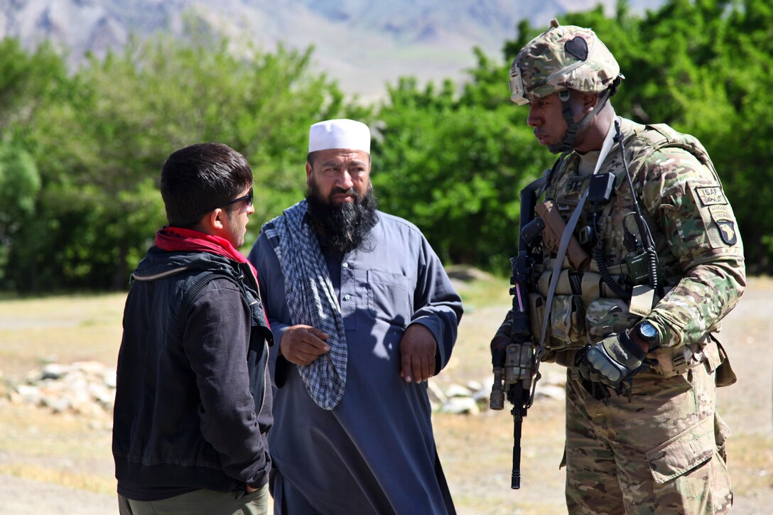 U.S. Army Capt. Rodney Freeman speaks with Afghan men during a humanitarian assistance mission near Bagram city in Afghanistan's Parwan province, May 2, 2014. Freeman is assigned to the 101st Airborne Division's 1st Battalion, 75th Cavalry Regiment.