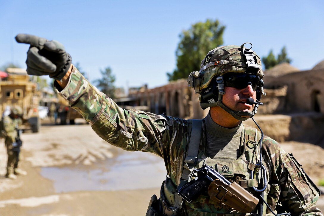 U.S. Army Sgt. 1st Class, Sal Somoza motions toward the justice center building to other soldiers while maintaining security during a meeting with the Farah provincial chief justice in Farah City, Afghanistan, May 4, 2013.  
