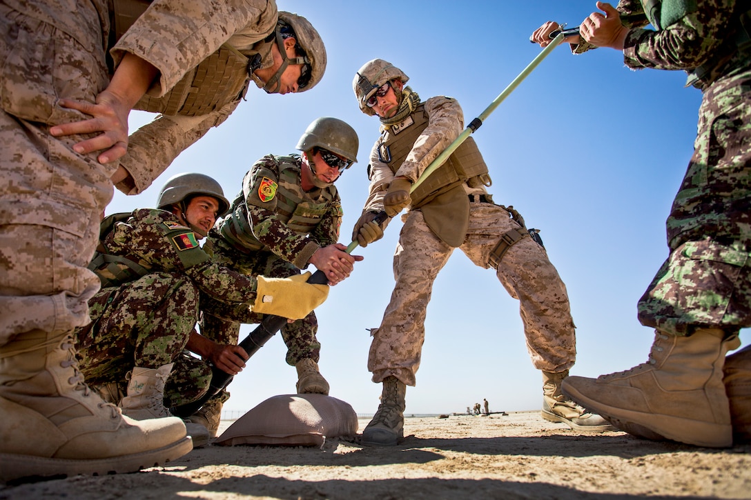 U.S. Marine Corps Staff Sgt. David Denseley, center, helps Afghan mortarmen clean the bore of a 60mm mortar at a mortar range near Camp Shorabak in Afghanistan's Helmand province, May 4, 2013. Denseley is assigned to the Regional Corps Battle School.  
