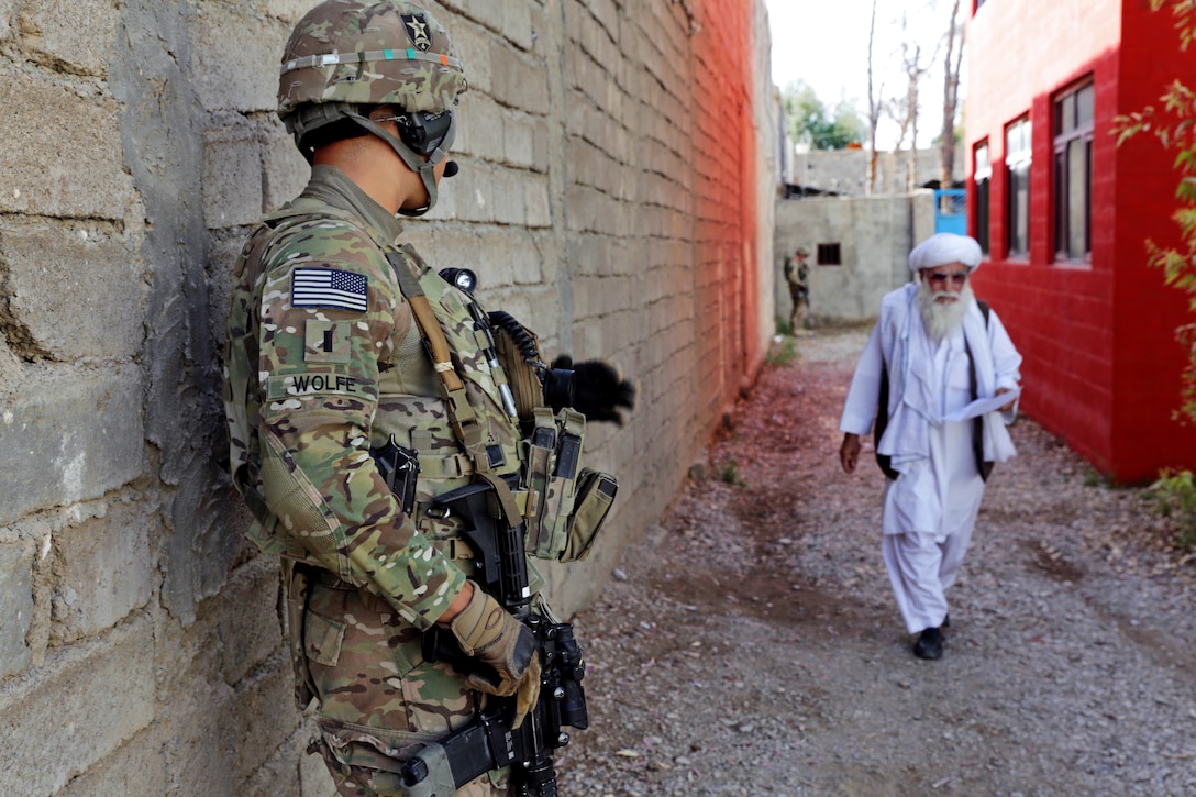 U.S. Army 1st Lt. Robert Wolfe waits to greet a Farah elder as he walks by during a meeting at the directorate of information and culture offices in Farah city, Afghanistan, April 10, 2013. Wolfe, a platoon leader, is assigned to Provincial Reconstruction Team Farah. 
