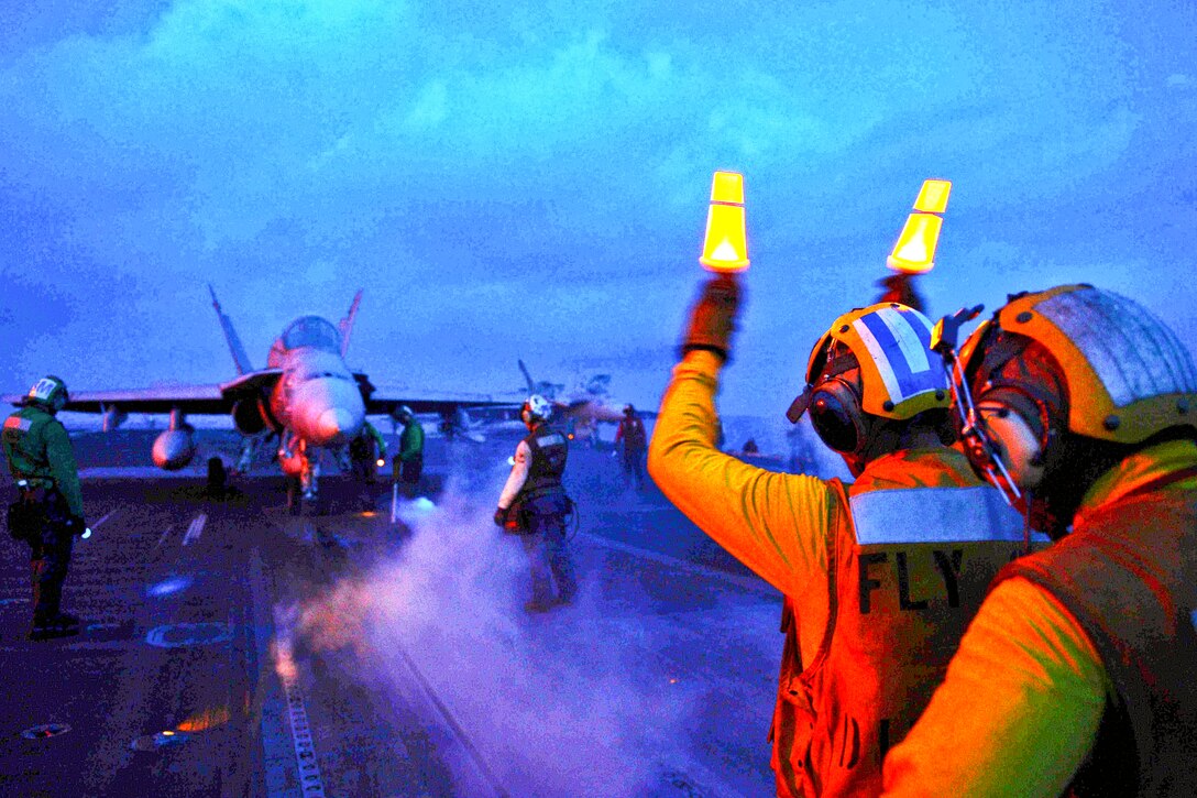 U.S. Navy Petty Officer 2nd Class Fernado Jimenez directs an aircraft on to a catapult on the flight deck of the aircraft carrier USS John C. Stennis in the South China Sea, April 6, 2013. The Stennis is deployed to the U.S. 7th Fleet area of responsibility conducting maritime security operations and theater security cooperation efforts. 
