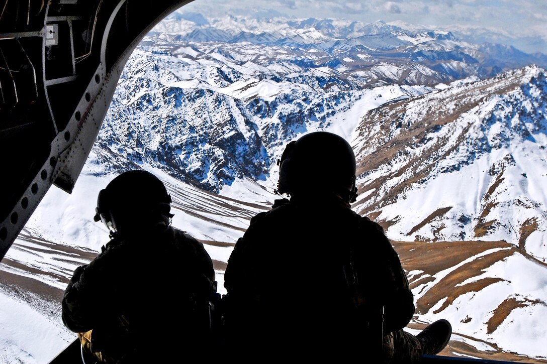 U.S. soldiers watch from the rear ramp of a CH-47 Chinook helicopter while flying over the mountains in the Khas Uruzgan district of Afghanistan's Uruzgan province, March 16, 2013. The soldiers are crew chiefs, who along with Afghan commandos, provided security for a government-led shura, or meeting.  
