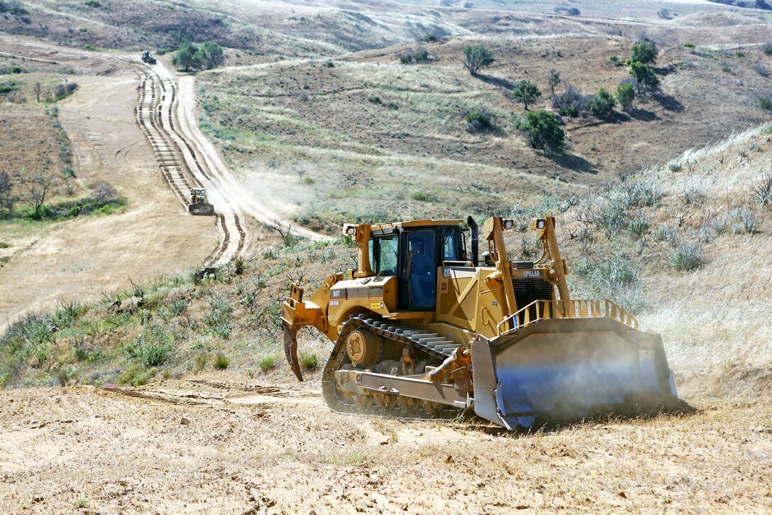 Lance Cpl. Matthew Brown, engineer equipment operator, Support Company, 7th Engineer Support Battalion, 1st Marine Logistics Group, plows brush along a firebreak path using a V8T Dozer aboard Camp Pendleton, Calif., May 13, 2014. Facilities Maintenance Division and seven Marines with 7th ESB, 1st MLG, began creating firebreaks May 6, 2014 in an effort to contain wildfires that may start on base and will continue to create them through Aug. 10, 2014. The FMD employees and 7th ESB Marines are still slated to meet this completion date even with the fire that destroyed 6,000 acres and caused hundreds of service members and their families to evacuate their on-base homes, May 14, 2014.