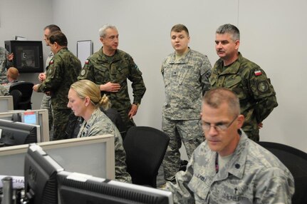 Illinois Army National Guard Spc. Slawomir Latka, with Company C, 341st Military Intelligence, 65th Troop Command (standing center) explains earthquake response operations to Lt. Col. Piotr Lisowski (left) and Maj. Zbgniew Smykovski (right) of the Polish Land Forces.
