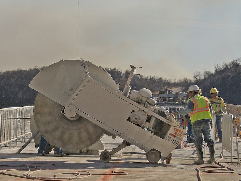 “The Beast,” a giant concrete saw with a 6-foot blade, prepares to cut through the deck of the Highway 151 Bridge over Keystone Dam. The aging structure is being replaced and the existing bridge deck must be removed. The saw cuts the bridge deck into sections and a Gantry Crane lifts the section onto a flatbed truck for removal.                  