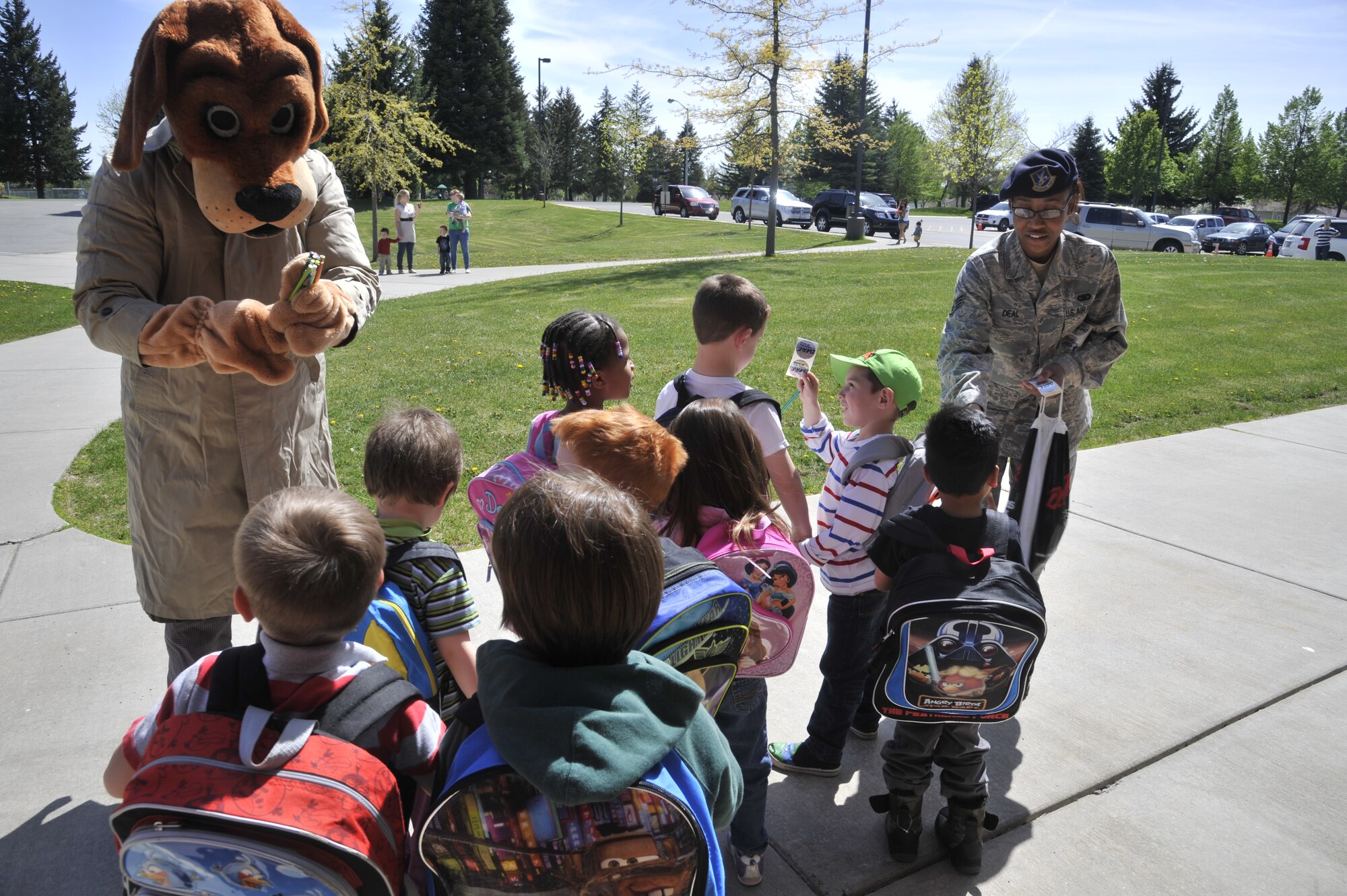 Scruff McGruff the Crime Dog and Staff Sgt. Denine Deal pass out pencils and stickers to a group of children from Michael Anderson Elementary School at Fairchild Air Force Base, Wash., May 14, 2014. McGruff and Deal spoke with children about staying safe and being aware of their surroundings. (U.S. Air Force photo by Senior Airman Mary O'Dell/Released)