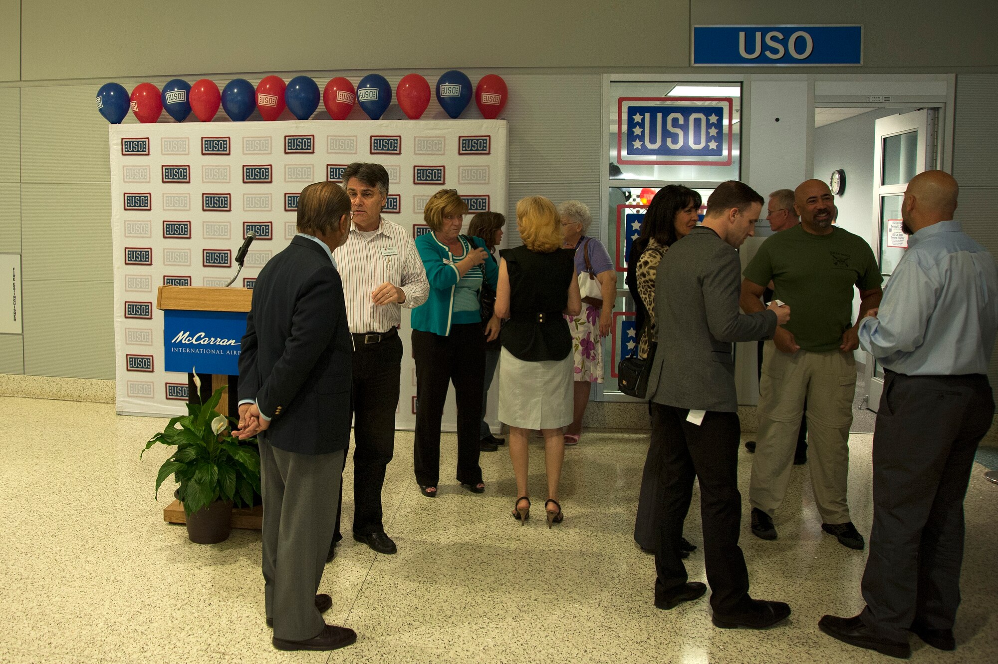 Guests and volunteers discuss USO programs and enjoy cake after the grand opening ceremony for a second USO lounge at McCarran International Airport located in Terminal 3 May 7, 2014. The addition of a second USO lounge location at McCarran gives the USO an opportunity to expand services to more customers each year. (U.S. Air Force photo by Tech. Sgt. S.E./Released)