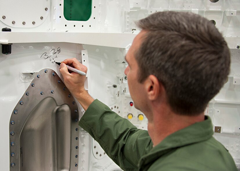 Col. Bryan Radliff, 419th Fighter Wing commander, signs the wing of the F-35A Lightning II due to arrive at Hill Air Force Base, Utah, in 2015. Radliff and his active-duty counterpart, Col. Lance Landrum, 388th FW commander, toured Lockheed Martin Aeronautics in Fort Worth, Texas, last week. (Courtesy photo)