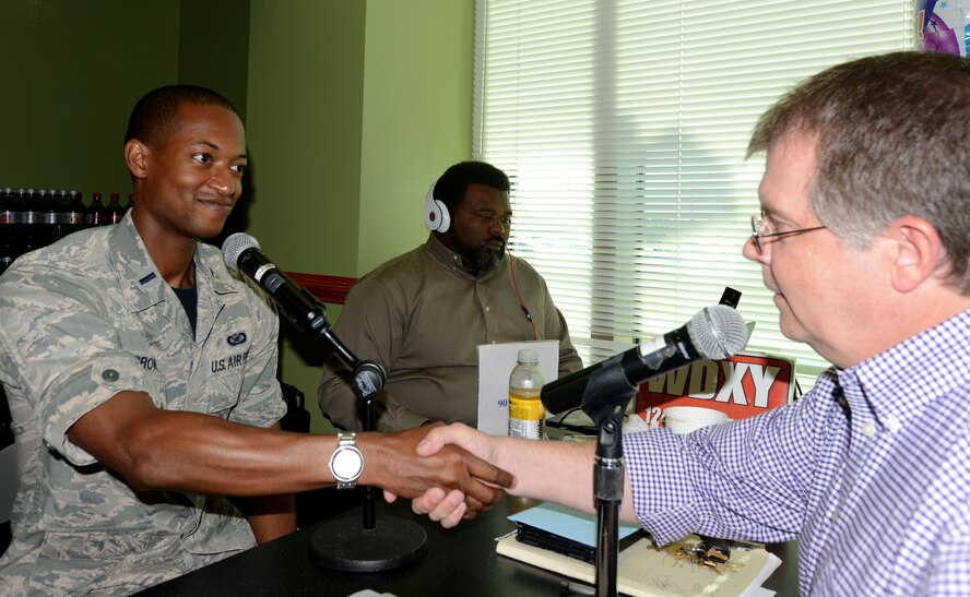 U.S. Air Force 1st Lt. Earon Brown, 20th Fighter Wing Public Affairs officer, shakes hands with Derek Burress, Miller Communications air personality, during a radio show segment May 16, 2014, at Shaw Air Force Base, S.C. Bi-monthly, the 20th FW and U.S. Army Central Command Public Affairs offices host Burress for special segments of his daily radio show, “Good Morning Sumter!,” entitled, “Touching Base.” Each show features Airmen and soldiers from across the base sharing their jobs and upcoming events Shaw AFB’s community partners. (U.S. Air Force photo by Senior Airman Laura L. Valentine/Released)