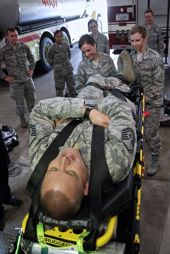 Lead instructor for the Emergency Medical Technician (EMT) refresher class, Master Sgt. Mathew Gerdes, takes on the role of patient as two Airman practice loading an ambulance as part of their skills training, May 16, at the Scott Air Force Base main fire station.  Medical technicians with the 932nd Medical Group are EMT certified and go through a refresher class every 2 years.  (U.S. Air Force photo by Tech. Sgt. Christopher Parr)  