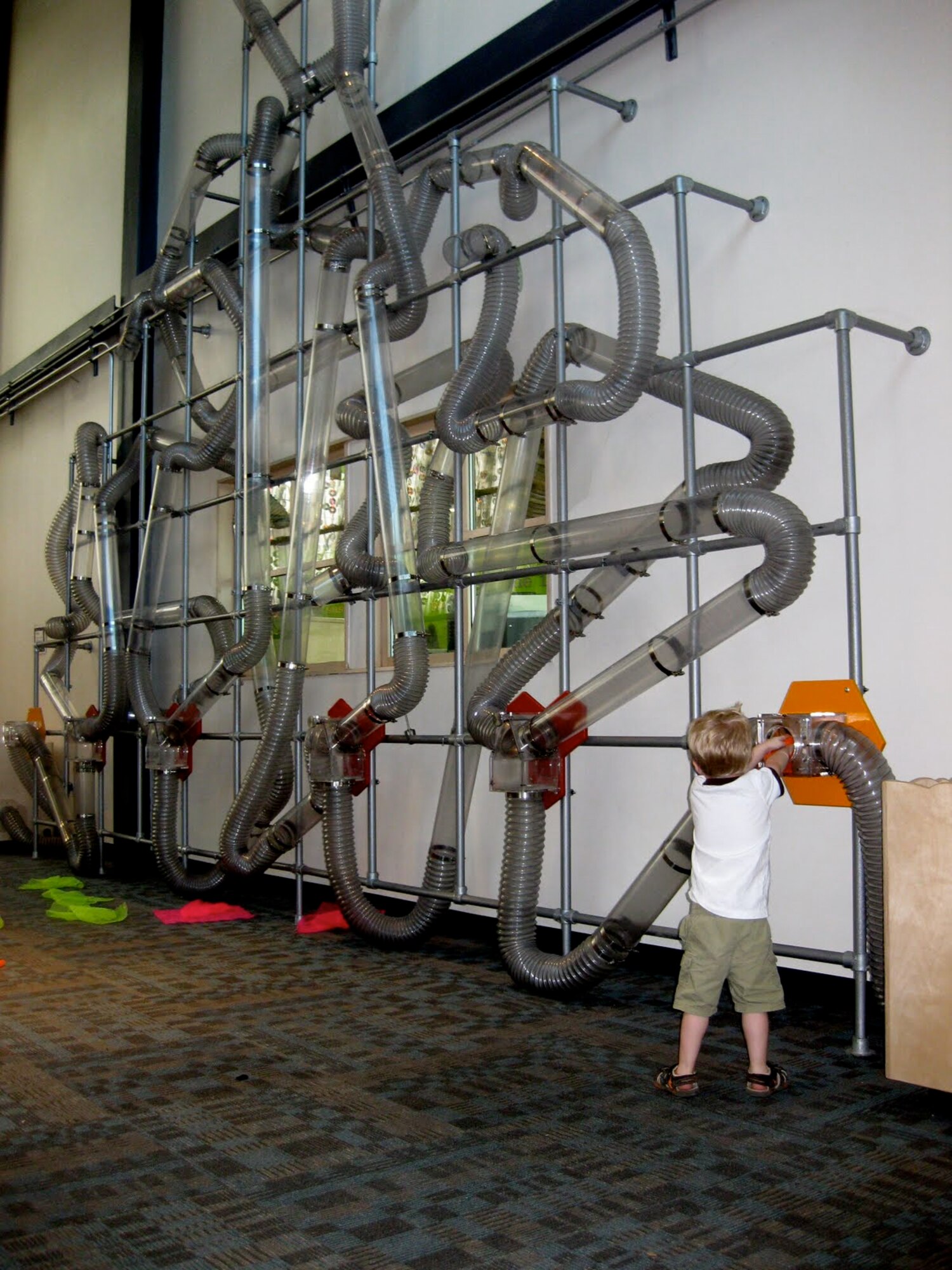 A child inserts a handkerchief into tubes with pressurized air flowing through. The handkerchief follows a path and shoots out of an opening on the other end. (Courtesy photo)  
