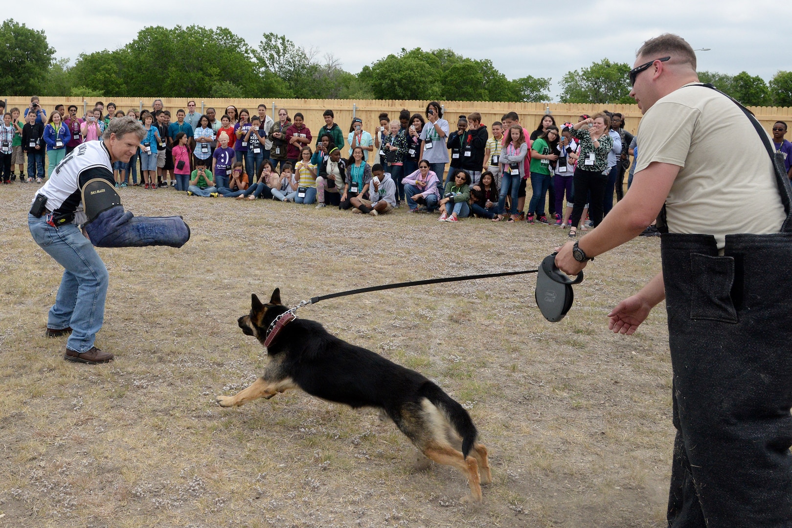 Air Force Staff Sgt. Johnathan Royce, 902nd Security Forces, commands Ramon, a military working dog, to attack Michael McFalls, Kitty Hawk Middle School Principal, as he simulates being a suspect during a demonstration for sixth graders May 6 at Kitty Hawk Middle School in Universal City, Texas. (U.S. Air Force photo by Johnny Saldivar)

