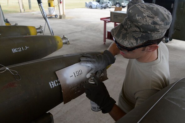 U.S. Air Force Senior Airman Beau Ridges, 20th Equipment Maintenance Squadron munitions flight munitions support equipment maintainer, uses spray paint to stencil the lot number on a MK-82 missile during a live bomb build at Shaw Air Force Base, S.C., May 15, 2014. When the missile is dropped from an airplane and hits the ground, three explosions take place within the bomb when it detonates. The Airmen are in charge of making sure the bomb is properly put together and all appropriate wires are connected. (U.S. Air Force photo by Airman 1st Class Michael A. Cossaboom/Released)