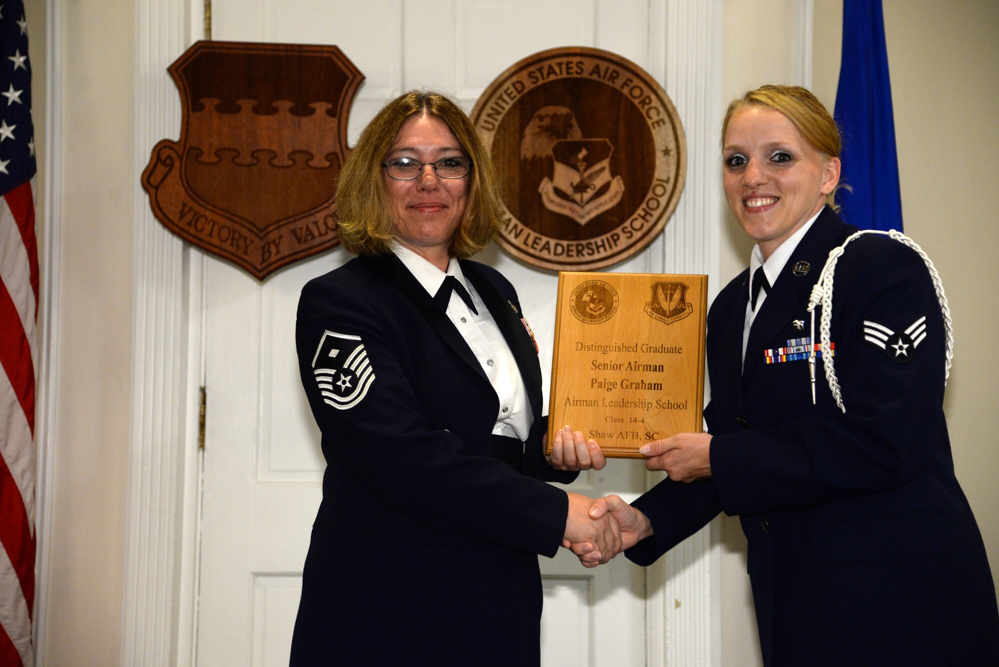 U.S. Air Force Senior Airman Paige Graham, 20th Medical Support Squadron (right), receives a distinguished graduate Award for class 14-4 of the Senior Master Sgt. David B. Reid Airman Leadership School from Master Sgt. Rhonda Roman, 20th Component Maintenance Squadron first sergeant, at Shaw Air Force Base, S.C., May 15, 2014. The distinguished graduate awards are given out to the top 10 percent of the class for total point accumulation. (U.S. Air Force photo by Airman 1st Class Jonathan Bass/Released)