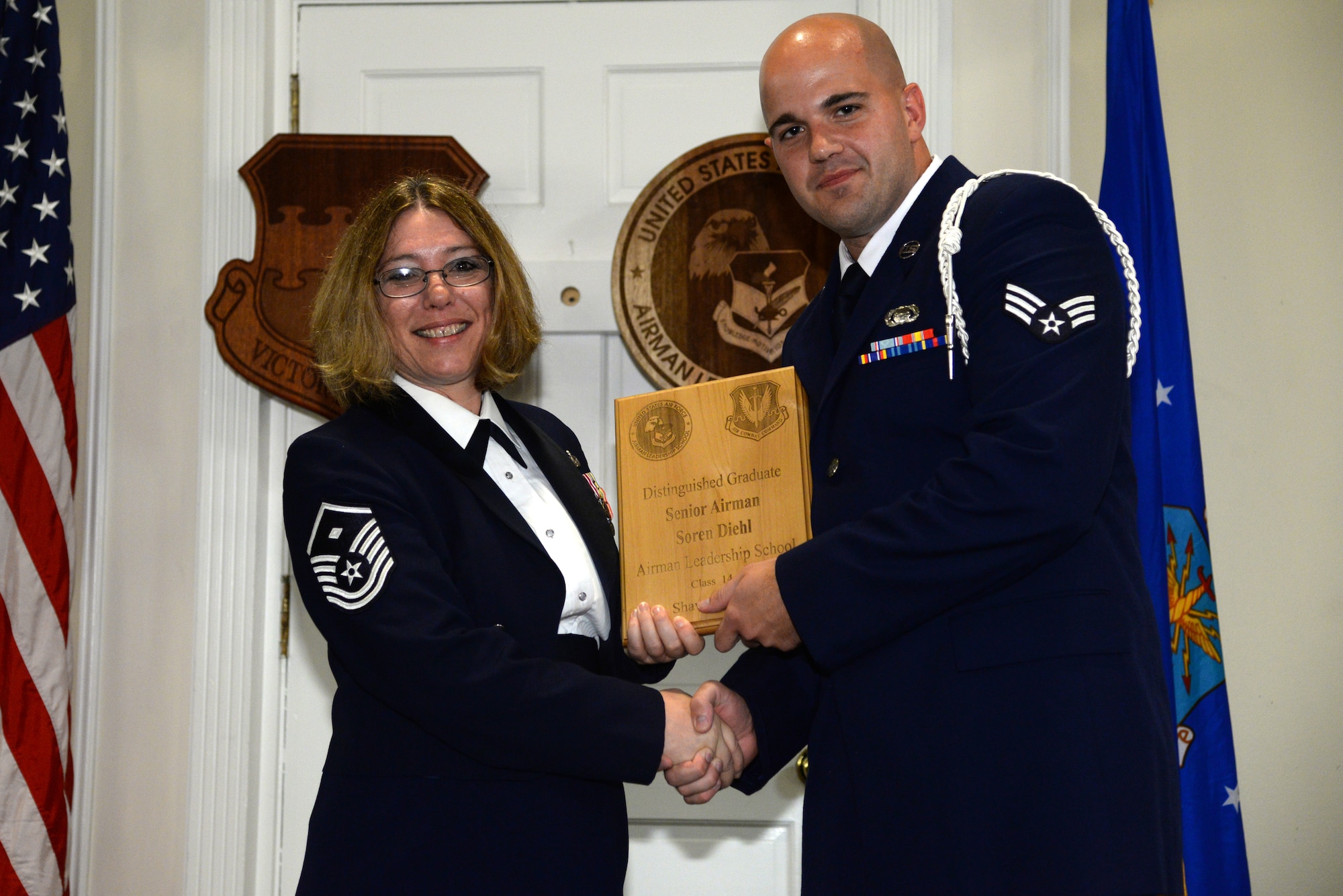U.S. Air Force Senior Airman Soren Diehl, 3rd Intelligence Squadron (right), receives a distinguished graduate Award for class 14-4 of the Senior Master Sgt. David B. Reid Airman Leadership School from Master Sgt. Rhonda Roman, 20th Component Maintenance Squadron first sergeant, at Shaw Air Force Base, S.C., May 15, 2014. The distinguished graduate awards are given out to the top 10 percent of the class for total point accumulation. (U.S. Air Force photo by Airman 1st Class Jonathan Bass/Released)