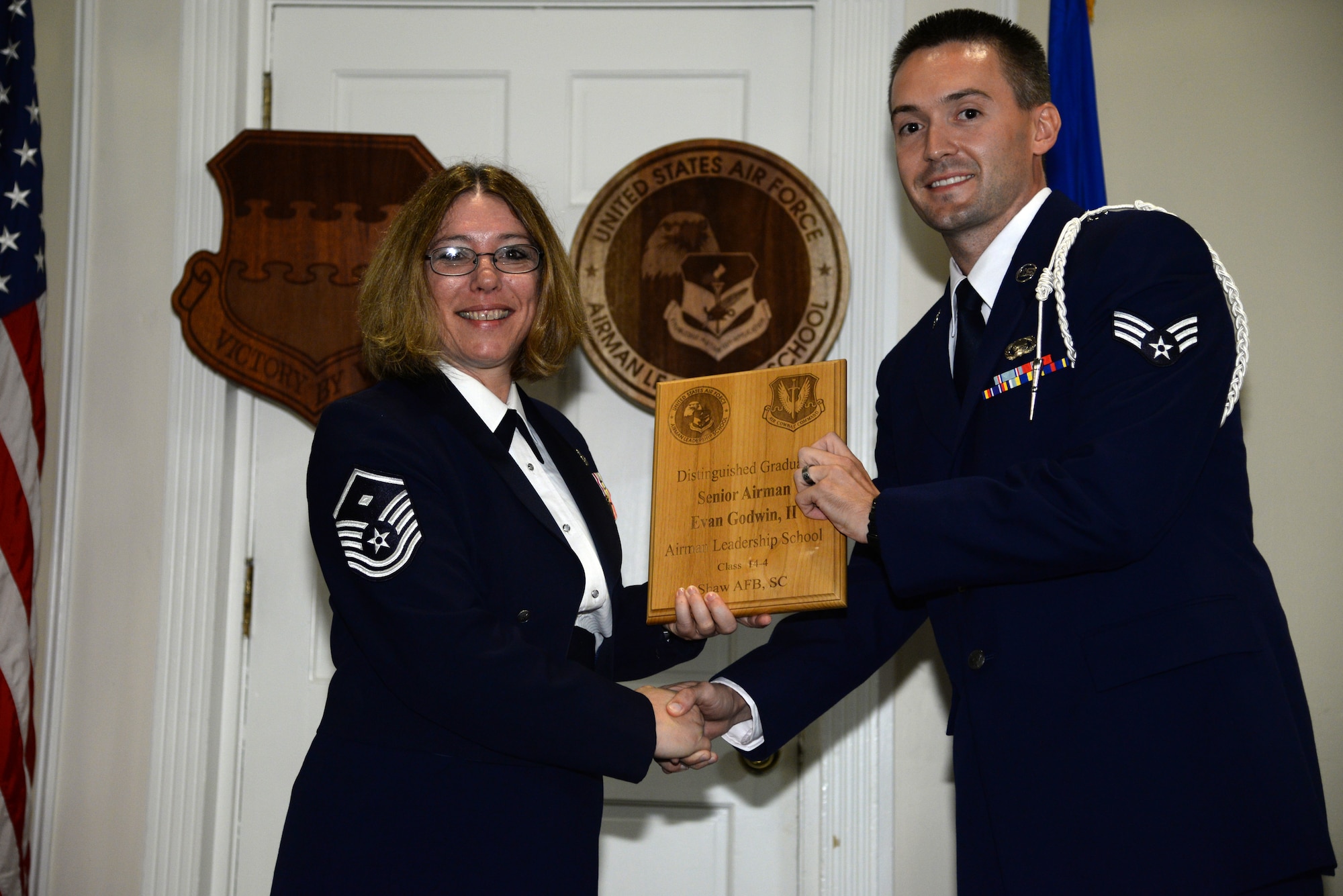 U.S. Air Force Senior Airman Evan Godwin II, 31st Intelligence Squadron (right), receives a distinguished graduate Award for class 14-4 of the Senior Master Sgt. David B. Reid Airman Leadership School from Master Sgt. Rhonda Roman, 20th Component Maintenance Squadron first sergeant, at Shaw Air Force Base, S.C., May 15, 2014. The distinguished graduate awards are given out to the top 10 percent of the class for total point accumulation. (U.S. Air Force photo by Airman 1st Class Jonathan Bass/Released)