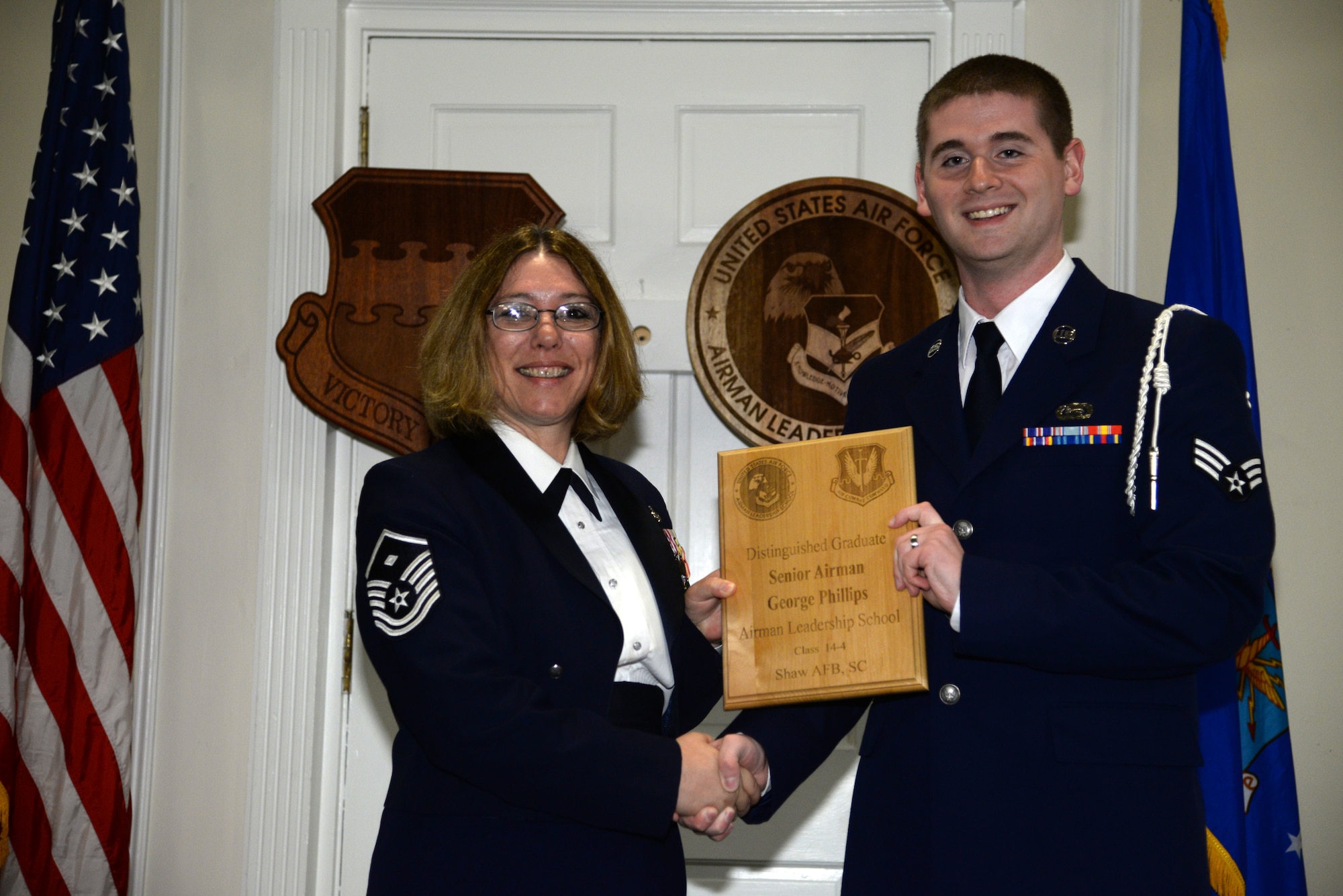 U.S. Air Force Senior Airman George Phillips, 3rd Intelligence Squadron (right), receives a distinguished graduate Award for class 14-4 of the Senior Master Sgt. David B. Reid Airman Leadership School from Master Sgt. Rhonda Roman, 20th Component Maintenance Squadron first sergeant, at Shaw Air Force Base, S.C., May 15, 2014. The distinguished graduate awards are given out to the top 10 percent of the class for total point accumulation. (U.S. Air Force photo by Airman 1st Class Jonathan Bass/Released)
