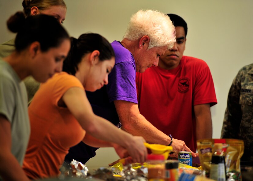 Airmen from the 436th Airlift Wing and Dorm to Gourm class instructors prepare a meal at the Health and Wellness Center May 13, 2014 at Dover Air Force Base, Del. Dorm to Gourm is a a cooking class offered to dorm residents that teaches them how they can prepare healthy and delicious meals. (U.S. Air Force photo/Staff Sgt. Elizabeth Morris)