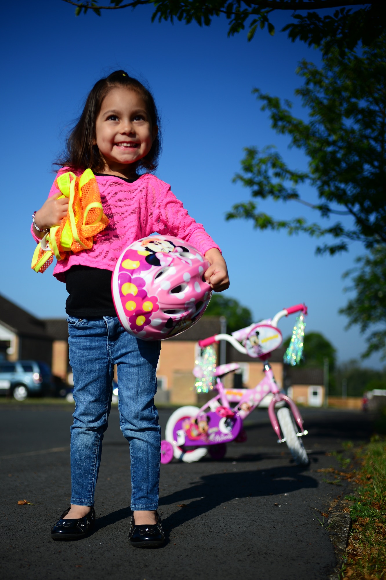 Kaileena Nuñez, daughter of Staff Sgt. Emerson Nuñez, 48th Fighter Wing Public Affairs photojournalist, gathers the proper safety gear before riding her bike on Royal Air Force Lakenheath, England, May 15, 2014. Reflective clothing and a helmet are required for all personnel when using any human-powered vehicle. (U.S. Air Force photo by Staff Sgt. Emerson Nuñez/Released)