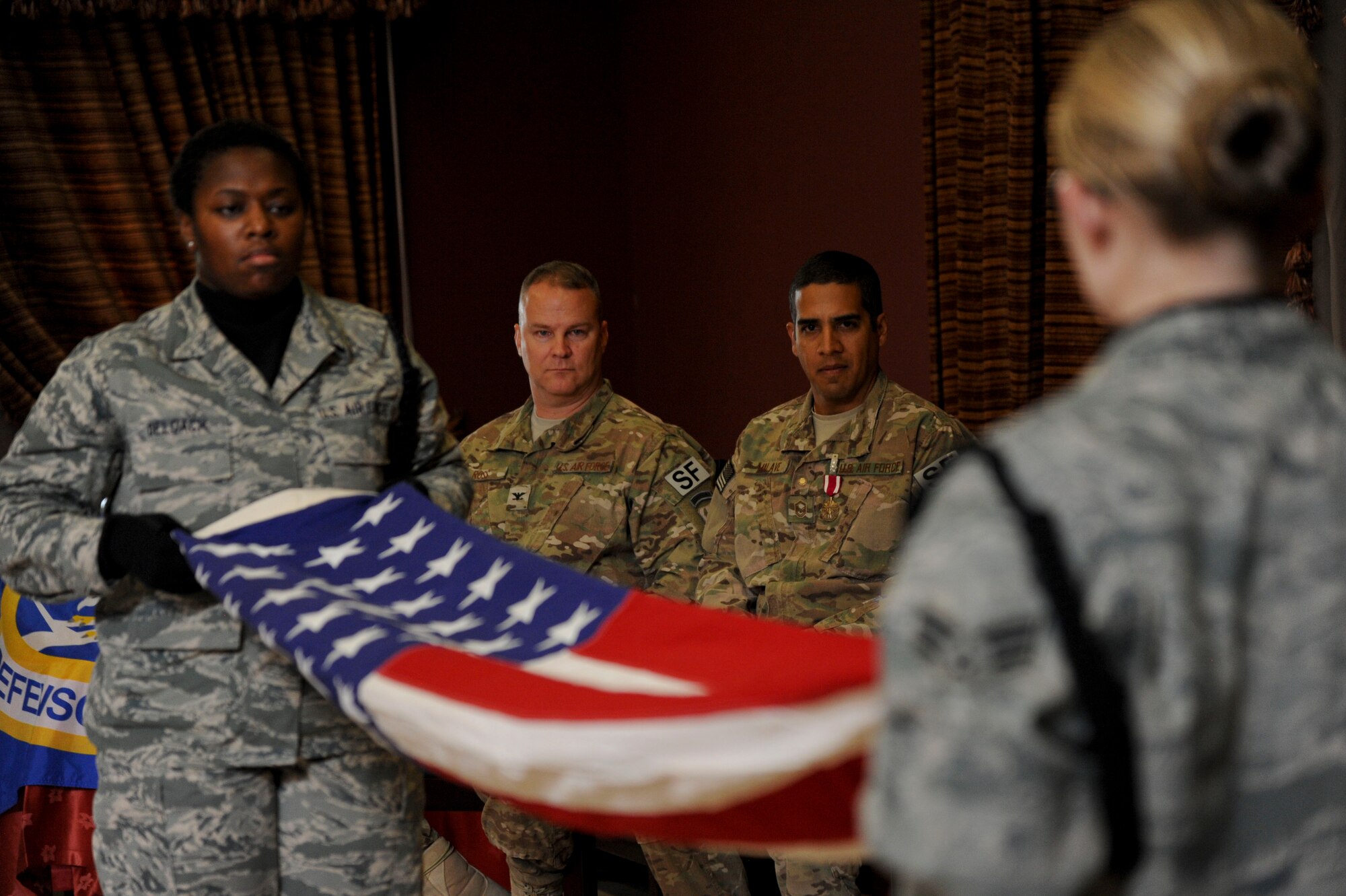 Master Sgt. Alexander Malave, U.S. Air Forces Central Command force protection NCO in charge, looks on as members from the 379th Air Expeditionary Wing honor guard, Al Udeid Air Base, Qatar, conduct a flag-folding ceremony during his retirement, May 9, 2014. (U.S. Air Force photo by Senior Airman Michael Ellis/Released)