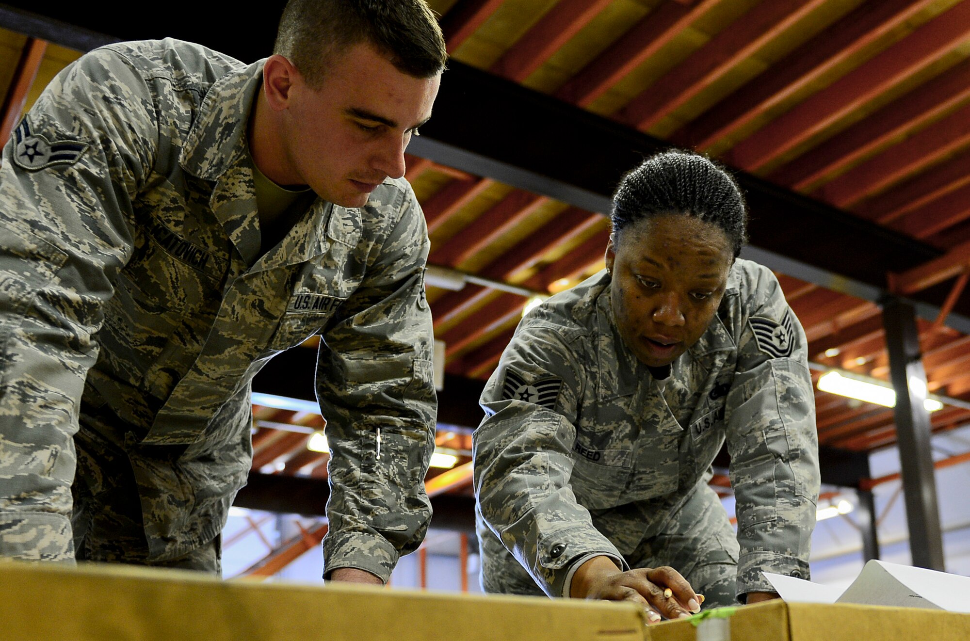 Tech. Sgt. Charmaine Reed (right) teaches Airman 1st Class Eric Licatovich about incoming packaging slip procedures at Royal Air Force Lakenheath, England, May 15, 2014. Reed, 48th Logistics Readiness Squadron flight service center NCO in charge, was nominated for a Liberty Spotlight because she displays the core value of Service Before Self. Licatovich is a 48th LRS flight service center apprentice. (U.S. Air Force photo by Airman 1st Class Dawn M. Weber/Released)