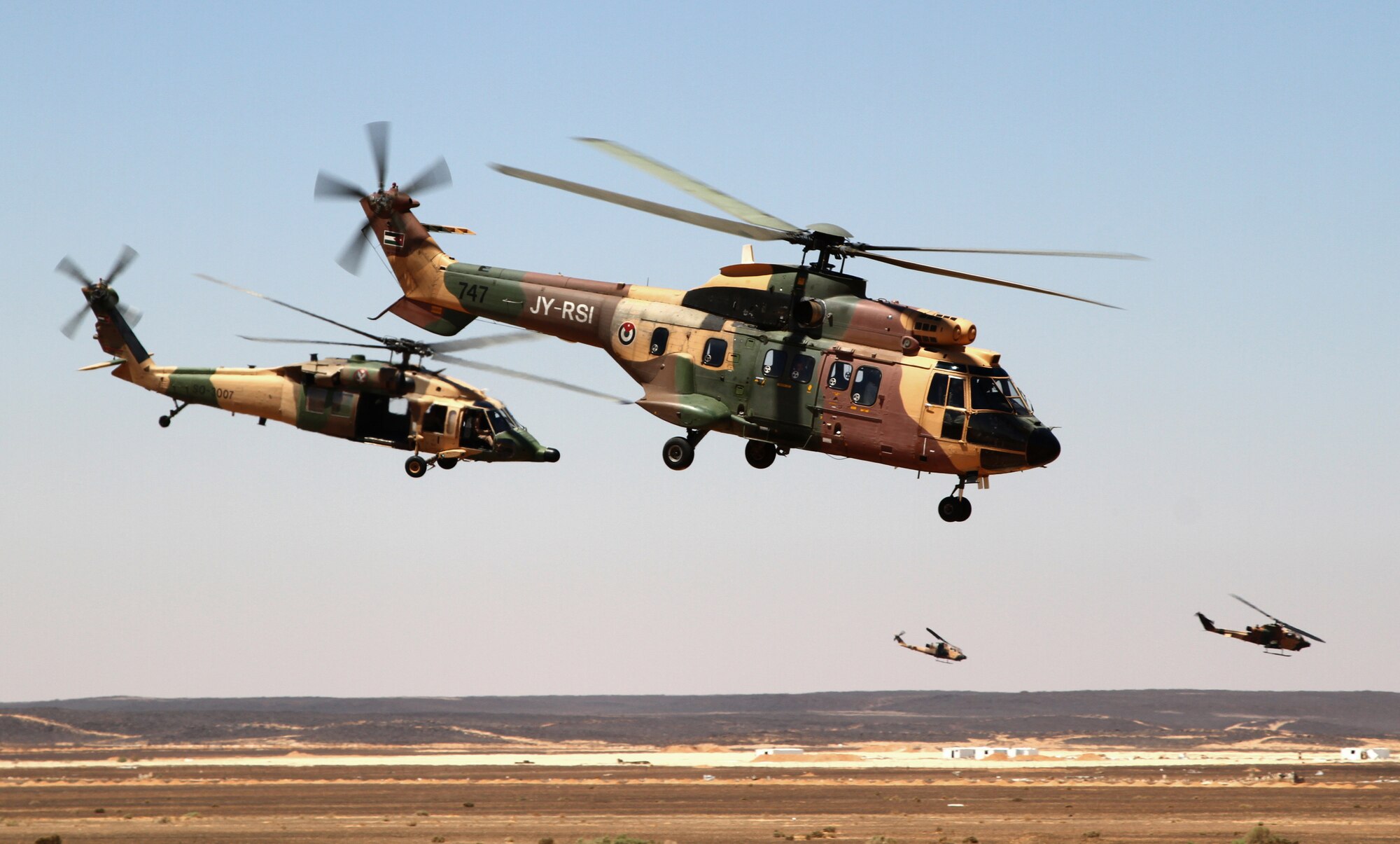 AS332 Super Puma and AH-1 Cobra helicopters from the Royal Jordanian Armed Forces fly away after dropping off special operations forces during a demonstration at Exercise Eager Tiger May 14, 2014, at an air base in northern Jordan. Fighter aircraft from the U.S. and Jordanian militaries also participated in the event, which signaled the final competition of this annual exercise. (U.S. Air Force photo by Staff Sgt. Tyler McLain/Released)
